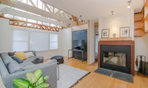modern living room with vaulted ceilings, large windows, a sectional sofa, a fireplace, and a TV setup